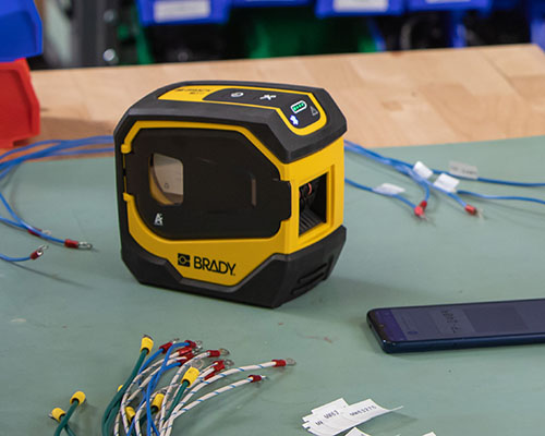 M511-printeren med opmærkede ledninger og en mobiltelefon.