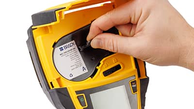 En rulle labelmateriale sættes i en M710-printer.