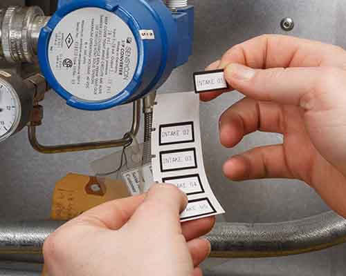 En person, som sætter labels fra en M610-printer på en maskine.